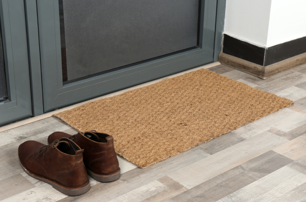 Coir mat outside a front door, with a pair of leather boots.